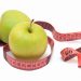 two green apples with a measuring tape around them